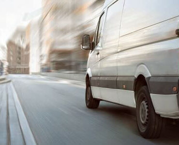 Weißer Transporter in Bewegung vor verschwommener Kulisse – Sprinter mieten